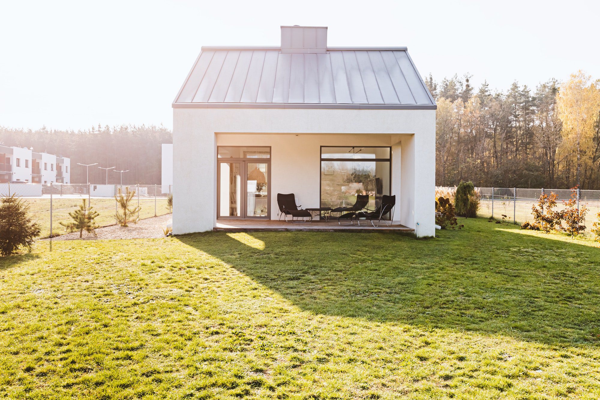 Modern garden furniture on the terrace of stylish suburban house with big green yard